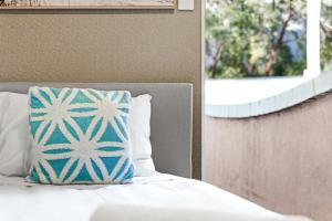 ein Bett mit einem blauen und weißen Kissen darauf in der Unterkunft Boutique Single Room - Centrally Located at Granville -In Courtyard - Shared Bathroom & Kitchen in Sydney
