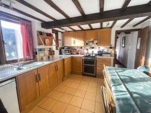 a kitchen with wooden cabinets and a table in it at Duvale Barn in Bampton