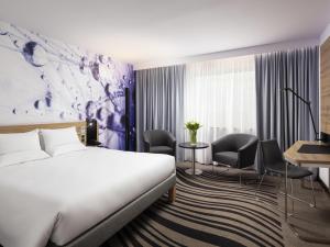 a hotel room with a bed and a desk and chairs at Novotel Poznan Centrum in Poznań +54 photos