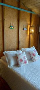 a bed with two pillows and two lights on the wall at Suite Shambhala Ideal para Casal Beira Mar entre Paraty e Ubatuba in Ubatuba