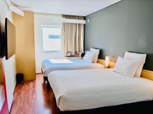 a hotel room with two beds and a window at Ibis Monterrey Valle in Monterrey
