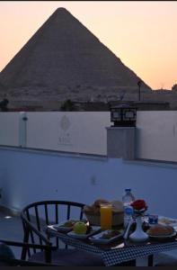 Una mesa con comida y una pirámide al fondo. en Kanz Pyramids Inn, en El Cairo