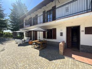 a patio with a table and an umbrella in front of a building at Case Vista Alta Langa in Cravanzana