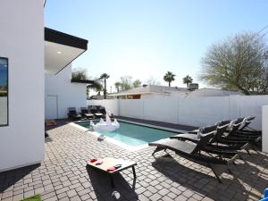 a swimming pool with chairs and a person in a swimming pool at LUXE - Nouveau - Sparkling Pool - Walk to Old Town in Scottsdale