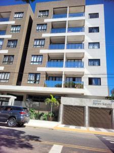 un'auto parcheggiata di fronte a un edificio alto di Apartmento em Castelhanos a 50 metros da praia a Anchieta