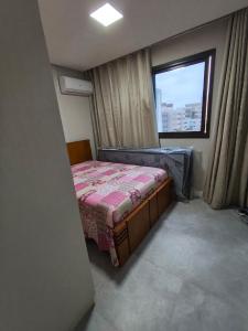una piccola camera da letto con un letto e una finestra di Apartmento em Castelhanos a 50 metros da praia a Anchieta