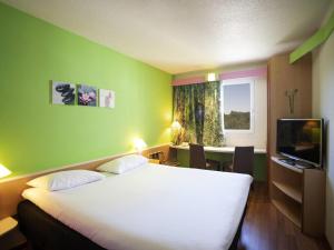 a hotel room with a large bed and a desk at ibis Fribourg in Fribourg