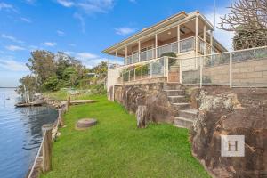 a house on a rock next to the water at Tide view in Toukley