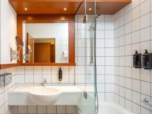 a bathroom with a sink and a mirror and a tub at Hotel Mercure Wien Westbahnhof in Vienna