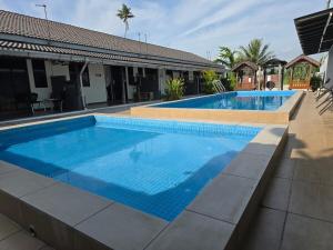 a large swimming pool with blue water at Homestay Tok Ani by Ardzman Hospitality in Permatang Pauh +8 photos