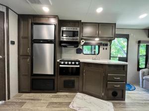 an rv kitchen with stainless steel appliances and wooden cabinets at Comfortable 1BR RV for mid-to-long term stays in Beaumont +8 photos