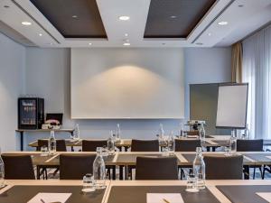 a classroom with tables and chairs and a projection screen at Mercure Hotel Hamburg Mitte in Hamburg