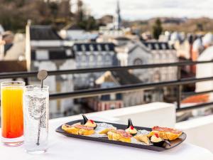 a plate of food on a table with a drink at Mercure Lourdes Impérial in Lourdes