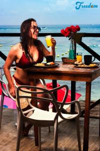 a woman in a bikini sitting at a table with a drink at Freedom Beach Club in Barú