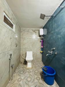 a bathroom with a toilet and a blue bucket at Aras homestay hampi in New Hampi +9 photos