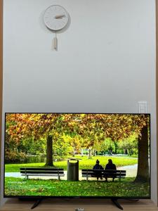 two people sitting on benches in a park with a clock at Seaside Mood 2BR near Gwangalli in Busan
