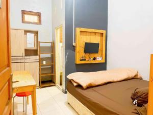 a bedroom with a bed and a desk and a tv at Griya Barokah Solo in Purwosari