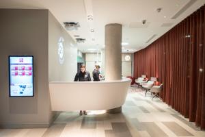 two people standing at a counter in a lobby at ibis Edinburgh Centre South Bridge – Royal Mile in Edinburgh