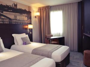 a hotel room with two beds and a window at Mercure Lyon Est Chaponnay in Chaponnay