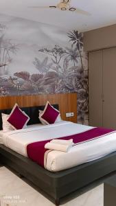 Un dormitorio con una cama grande con almohadas moradas. en Hotel Kiara Eshosans Palace, en Shirdi