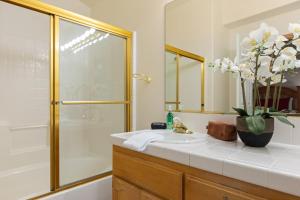 a bathroom with a sink and a shower and a vase of flowers at Alpine Retreat w Private Deck Views Outdoor Dining Alpen Drive by AvantStay in Lake Arrowhead +46 photos