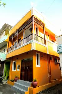 Buddha Home stay في مهاباليبورام: مبنى أصفر مع شرفة فوقه