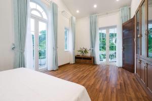 ein großes Schlafzimmer mit einem Bett und großen Fenstern in der Unterkunft Villa B82 Flamingo Đại Lải Resort in Phúc Yên