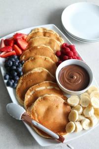 a plate of food with pancakes and fruit and chocolate at Частный дом в Бишкеке in Bishkek