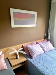 a bedroom with a bed with pink and purple pillows at Apartamento Aldeia das Águas l Condomínio Village das Águas in Barra do Piraí +11 photos