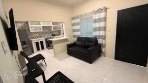 a living room with a black chair and a kitchen at The cozy spot negril in Negril