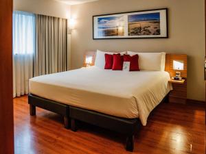 a hotel room with a large bed with red pillows at Novotel Lima San Isidro in Lima