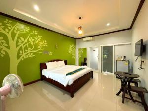 a bedroom with a green wall with a bed and a table at Monmai Resort Huahin in Hua Hin