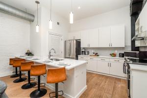 a kitchen with white cabinets and a kitchen island with bar stools at The Saddlery - Sound Check - 1 Block to Broadway in Nashville