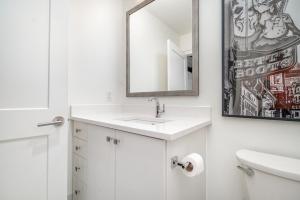 a white bathroom with a sink and a mirror at The Saddlery - Mic Drop - Walk to Broadway in Nashville +57 photos