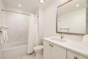 a white bathroom with a toilet and a sink at The Saddlery-Setlist-4 Combo Unit-Walk to Broadway in Nashville +116 photos