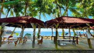 a beach with tables and chairs and palm trees at CABIN C at Bigang Munti Beach Resort in Bootin