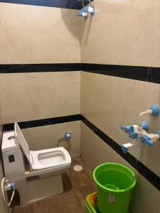 uma casa de banho com um WC e um balde verde em Hari Dham em Vrindāvan