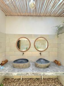 two sinks on a stone counter with two mirrors at Elisa Hostel in Kuta Lombok +10 photos