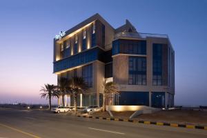 a building with palm trees in front of a street at Work meets comfort Studio by Spacey Duqm 78 in Duqm