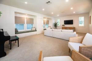 a living room with white furniture and a piano at Echo Beach House in One Mile