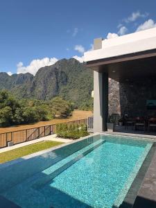 a swimming pool in front of a house with a mountain at Song View Pool Villa in Vang Vieng