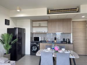 パタヤ・ノースにあるZire Wongamat Condoのテーブルと椅子、冷蔵庫のあるキッチン