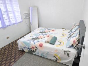 a bedroom with a bed with a floral comforter at Belle Go in Bauang