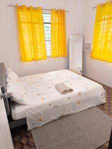 a bed in a room with two yellow windows at Belle Go in Bauang