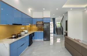 a large kitchen with blue cabinets and appliances at Zenda Villa Novaworld Phan Thiết in Bình Tú