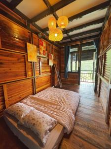 ein Schlafzimmer mit einem Bett in einem Zimmer mit Holzwänden in der Unterkunft Nhà Dưới Đồi Homestay in Ấp Man Ling