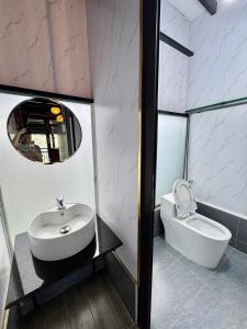 ein Badezimmer mit Waschbecken, Toilette und Spiegel in der Unterkunft Nhà Dưới Đồi Homestay in Ấp Man Ling