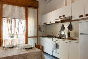 a kitchen with white cabinets and a table with a table cloth at Villa dei Fiori Apartments in Cervia +32 photos