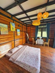 ein Schlafzimmer mit einem Bett und einem Tisch mit Stühlen in der Unterkunft Nhà Dưới Đồi Homestay in Ấp Man Ling