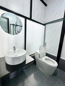 ein Badezimmer mit Waschbecken, Toilette und Spiegel in der Unterkunft Nhà Dưới Đồi Homestay in Ấp Man Ling